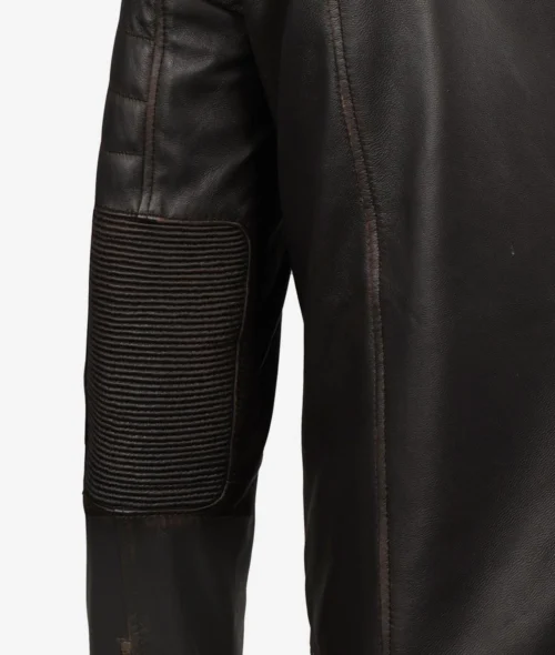 Close-up of a dark brown leather jacket sleeve featuring ribbed padding on the elbow area, with visible stitching. The material appears rugged and durable.
