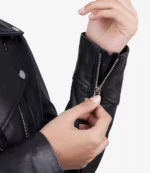 Close-up of a person zipping the cuff of a black leather jacket. The image highlights the texture of the material and the metallic zipper detail.