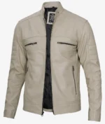 Beige leather jacket with a standing collar and quilted sleeves. Features four zip pockets and an open front, revealing a black inner lining. Stylish and modern.
