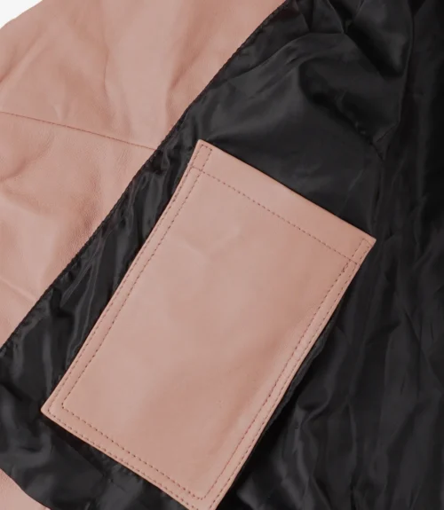 Close-up of a light pink leather jacket interior showcasing a rectangular pink pocket against a smooth black lining, emphasizing contrast and texture.
