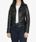A person wearing a fitted black leather jacket over a white t-shirt and dark blue jeans. The jacket has multiple zippered pockets and a sleek, modern design.