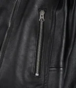 Close-up of a black leather jacket featuring a vertical silver zipper. The texture appears smooth, exuding a sleek, classic, and edgy style.