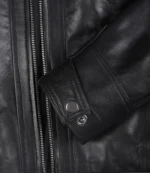 Close-up of a black leather jacket's sleeve with visible zipper and snap button detail. Texture appears smooth and polished, conveying a sleek, stylish tone.