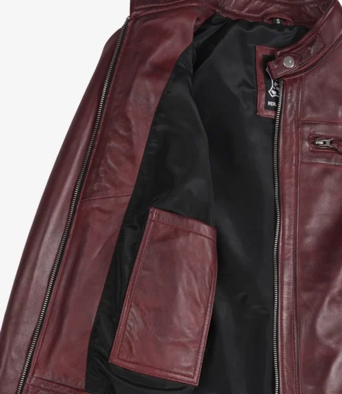 Open burgundy leather jacket showcasing its black inner lining and a large interior pocket. The jacket exudes a stylish, sleek tone.
