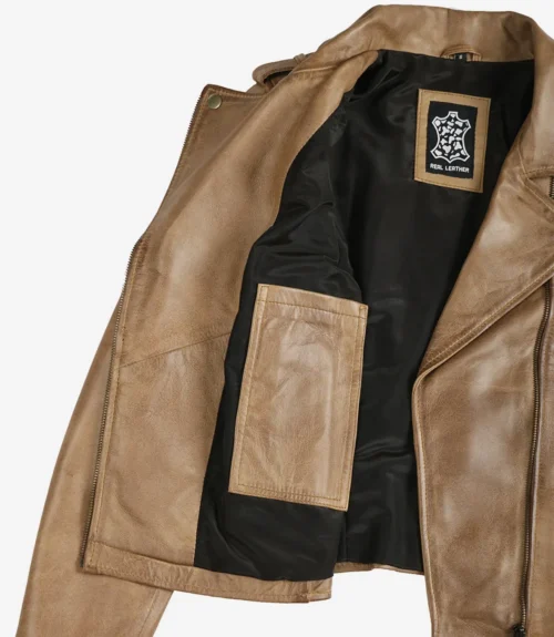 Tan leather jacket shown open, revealing black interior lining with a Real Leather label and an inner pocket. The tone is rugged and stylish.