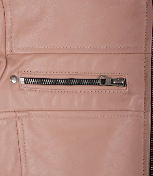 Close-up of a pink leather jacket featuring a horizontal silver zipper pocket with detailed stitching and a rivet on the upper left.