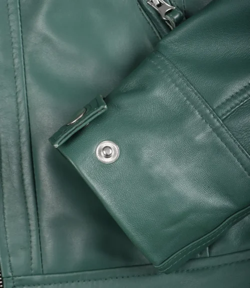 Close-up of a teal leather jacket showing detailed stitching, a snap button on the sleeve, and a silver zipper. The leather has a smooth texture.