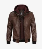 Brown leather jacket with a detachable hood in maroon, featuring multiple zippered pockets, shoulder epaulettes, and ribbed cuffs, conveying a rugged style.