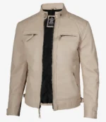 A beige leather jacket with a mandarin collar, front zipper, and flap pockets. It has quilted shoulder details and black inner lining, exuding a sleek, modern style.