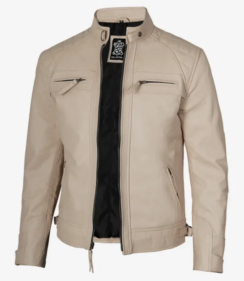 A beige leather jacket with a mandarin collar, front zipper, and flap pockets. It has quilted shoulder details and black inner lining, exuding a sleek, modern style.