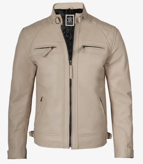 Tan leather jacket with a stand collar and quilted shoulders. Features four zippered pockets and a front closure, exuding a sleek, stylish vibe.