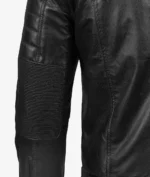 Close-up of a black leather jacket sleeve with ribbed detailing on the elbow. The sleek texture and stitching convey a modern and edgy style.