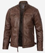Brown leather jacket with quilted shoulders, zippers on the chest and pockets, and a sleek finish. The jacket is open, revealing a dark interior lining.