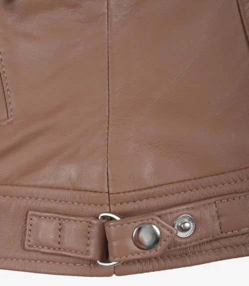 Close-up of a brown leather jacket's hem with visible stitching and a metal snap button. The texture is smooth, conveying a sleek, stylish look.