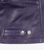 Close-up of a dark purple leather jacket with visible stitching. Features a metal snap button and rivet on a strap, conveying a sleek, stylish look.