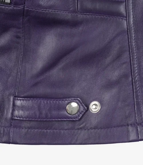 Close-up of a dark purple leather jacket with visible stitching. Features a metal snap button and rivet on a strap, conveying a sleek, stylish look.