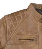 Close-up of a brown leather jacket featuring quilted shoulder detailing and a small zippered chest pocket. The leather has a rugged, textured appearance.