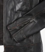 Close-up of a black leather jacket focusing on the sleeve, decorated with a prominent zipper. The material appears shiny, conveying a rugged, stylish tone.
