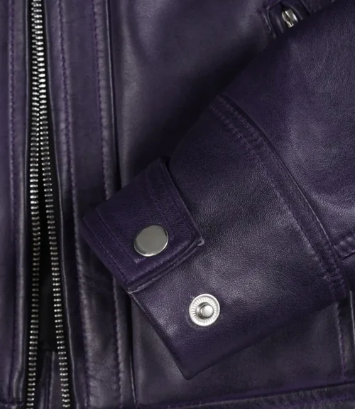 Close-up of a purple leather jacket showcasing a silver zipper and two snap buttons on the cuff, highlighting its sleek and stylish design.