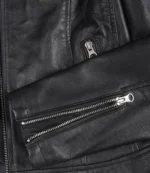 Close-up of a black leather jacket showcasing sleek zippers on the pocket and sleeve. The texture appears smooth and polished, giving a modern, stylish vibe.