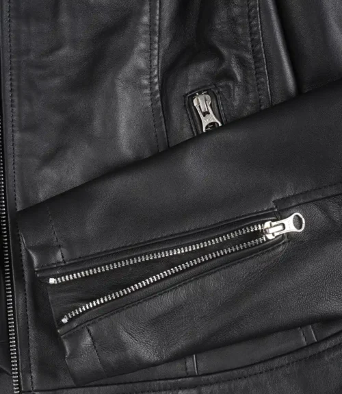 Close-up of a black leather jacket showcasing sleek zippers on the pocket and sleeve. The texture appears smooth and polished, giving a modern, stylish vibe.