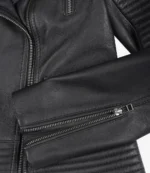 Close-up of a black leather jacket featuring silver zippers and quilted stitching. The sleek design conveys a modern and edgy style.