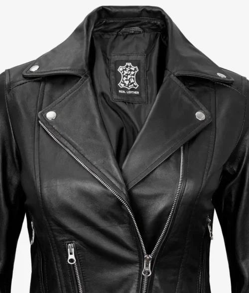 Close-up of a black leather biker jacket with silver zippers and buttons. The label inside reads Real Leather. The style is sleek and edgy.