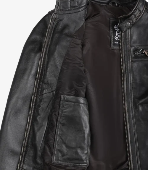 Close-up of an open dark brown leather jacket, revealing a smooth inner lining and a side pocket. The jacket conveys a sleek, stylish appearance.