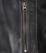 Close-up of a black leather jacket with a vertical silver zipper. The texture is smooth with visible stitching, exuding a sleek and stylish tone.