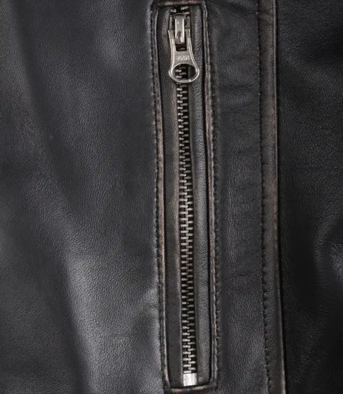 Close-up of a black leather jacket with a vertical silver zipper. The texture is smooth with visible stitching, exuding a sleek and stylish tone.