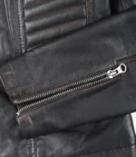 Close-up of a black leather jacket sleeve with a silver zipper. The texture is smooth and slightly worn, conveying a rugged, stylish appeal.
