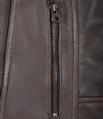 Close-up of a dark brown leather jacket showing a vertical zipper detail. The texture is smooth and slightly shiny, conveying a rugged, stylish vibe.