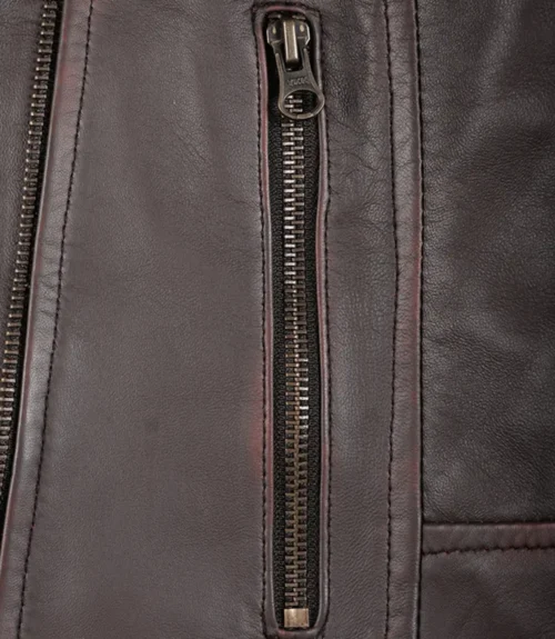 Close-up of a dark brown leather jacket showing a vertical zipper detail. The texture is smooth and slightly shiny, conveying a rugged, stylish vibe.