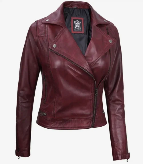 Maroon leather jacket with an asymmetrical zipper, notched collar, and silver snap buttons. It has a stylish, edgy appearance, exuding a bold, modern vibe.