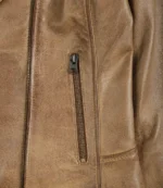 Close-up of a tan leather jacket pocket with a vertical zipper. The leather has a slightly worn texture, conveying a rugged, vintage aesthetic.