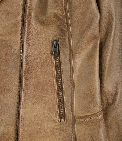 Close-up of a tan leather jacket pocket with a vertical zipper. The leather has a slightly worn texture, conveying a rugged, vintage aesthetic.