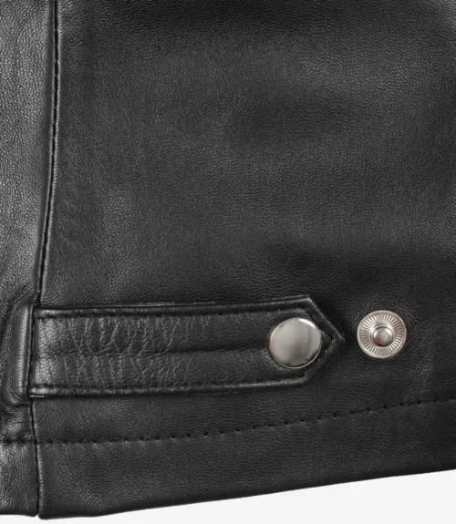 Close-up of black leather fabric with smooth texture, featuring two silver metal snaps on a strap near the edge, conveys a sleek and stylish tone.