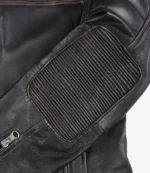 Close-up of a black leather jacket showing a textured, ribbed patch on the elbow and a silver zipper partly visible, conveying a rugged yet stylish look.