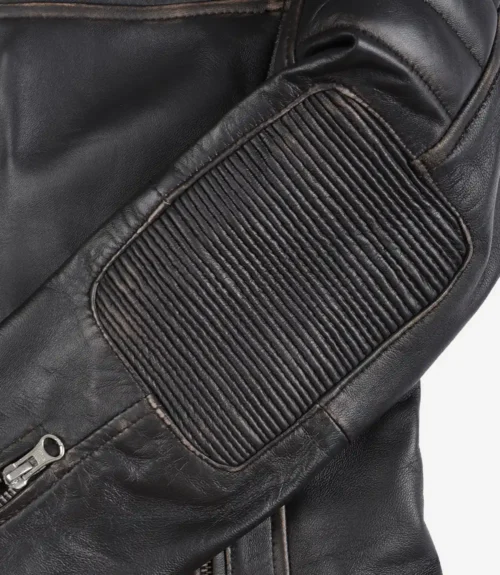 Close-up of a black leather jacket showing a textured, ribbed patch on the elbow and a silver zipper partly visible, conveying a rugged yet stylish look.