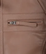 Close-up of a tan leather jacket showcasing a horizontal zippered pocket. The texture appears smooth and polished, conveying a sleek, stylish feel.