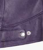 Close-up of a purple leather jacket featuring smooth texture and silver snap buttons. The stitching highlights the sleek, stylish design.