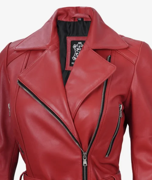 Close-up of a red leather motorcycle jacket with silver zippers and wide lapels, giving a bold and edgy feel. Black patch visible inside.