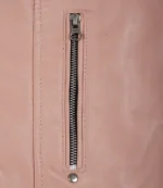 Close-up of a pink leather jacket showing a vertical silver zipper and stitching. The sleek texture and color give a stylish, modern feel.