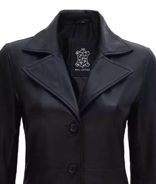 Black leather jacket with wide lapels and two front buttons. The label inside reads "Real Leather." The style is sleek and minimalist.