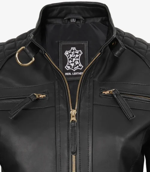 Black leather jacket with gold zipper, quilted shoulders, and D-ring detail. Label reads Real Leather with a leather pattern logo, conveying a sleek, stylish tone.