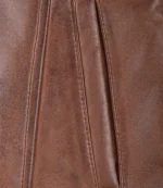 Close-up of a brown leather texture with visible stitching and folds. The leather has a smooth yet slightly textured appearance, conveying a sense of warmth and durability.